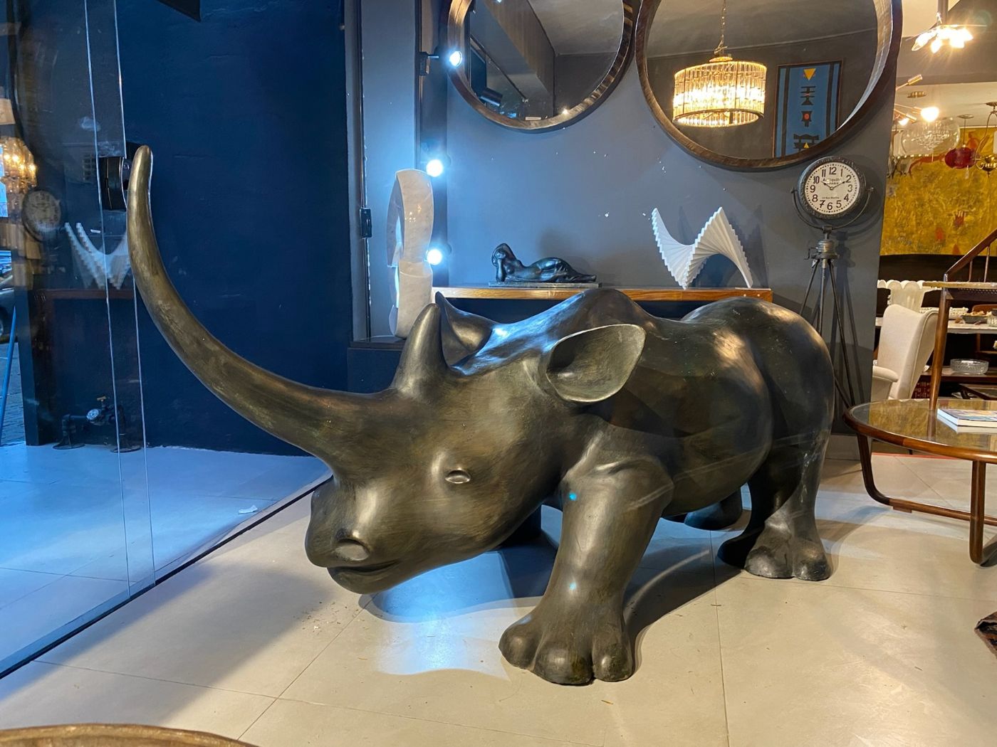 Escultura de rinoceronte em bronze diante de espelhos redondos